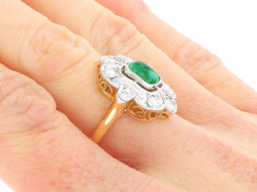 fig 9. An Art Deco dress ring featuring a central cushion-cut green emerald surrounded by a geometric pierced diamond halo set in white metal on an 18ct yellow gold band.