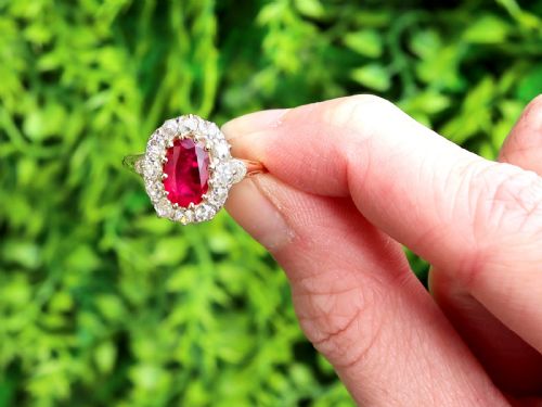 fig 1. An 18ct yellow gold ring featuring a central oval faceted ruby surrounded by a halo of twelve old cut diamonds in claw settings.