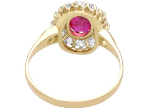 fig 5. An 18ct yellow gold ring featuring a central oval faceted ruby surrounded by a halo of twelve old cut diamonds in claw settings.