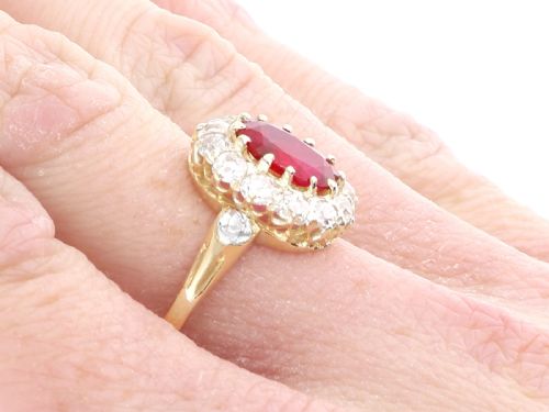 fig 8. An 18ct yellow gold ring featuring a central oval faceted ruby surrounded by a halo of twelve old cut diamonds in claw settings.