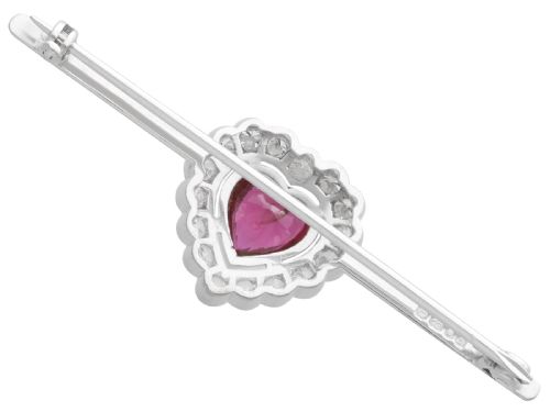 fig 5. A vintage 18k white gold bar brooch featuring a central heart-cut red ruby framed by a diamond halo, mounted on a slender polished bar.