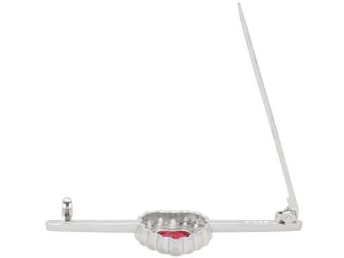 fig 6. A vintage 18k white gold bar brooch featuring a central heart-cut red ruby framed by a diamond halo, mounted on a slender polished bar.