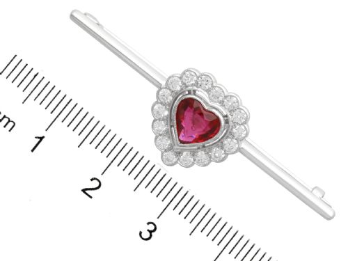fig 7. A vintage 18k white gold bar brooch featuring a central heart-cut red ruby framed by a diamond halo, mounted on a slender polished bar.