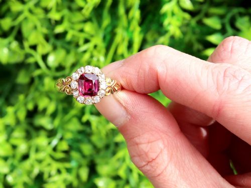 fig 1. An 18ct yellow gold Victorian cluster ring featuring a central cushion-cut red ruby framed by twelve hand-cut diamonds with carved scroll shoulders.