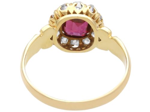 fig 5. An 18ct yellow gold Victorian cluster ring featuring a central cushion-cut red ruby framed by twelve hand-cut diamonds with carved scroll shoulders.