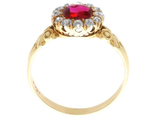 fig 6. An 18ct yellow gold Victorian cluster ring featuring a central cushion-cut red ruby framed by twelve hand-cut diamonds with carved scroll shoulders.