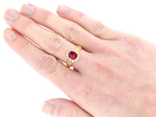 fig 7. An 18ct yellow gold Victorian cluster ring featuring a central cushion-cut red ruby framed by twelve hand-cut diamonds with carved scroll shoulders.