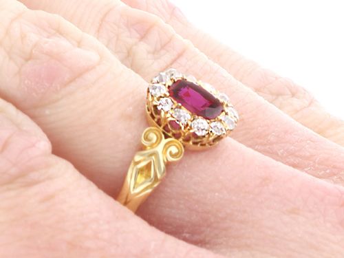 fig 8. An 18ct yellow gold Victorian cluster ring featuring a central cushion-cut red ruby framed by twelve hand-cut diamonds with carved scroll shoulders.
