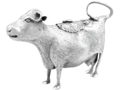 fig 5. An antique sterling silver cow creamer featuring textured hide detailing, a looped tail handle, and a floral hinged lid on its back.