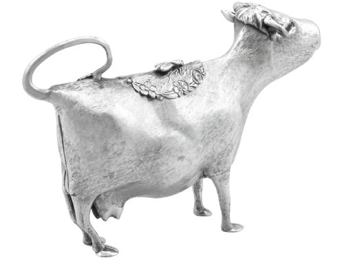 fig 6. An antique sterling silver cow creamer featuring textured hide detailing, a looped tail handle, and a floral hinged lid on its back.