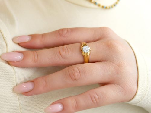 fig 4. An 18ct yellow gold solitaire ring featuring a round central diamond held in a claw setting with fluted shoulders.