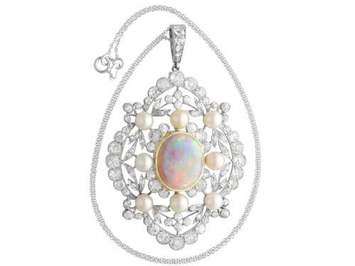 fig 3. An antique platinum pendant featuring a central oval cabochon opal set in gold, surrounded by natural saltwater pearls and openwork diamond filigree.