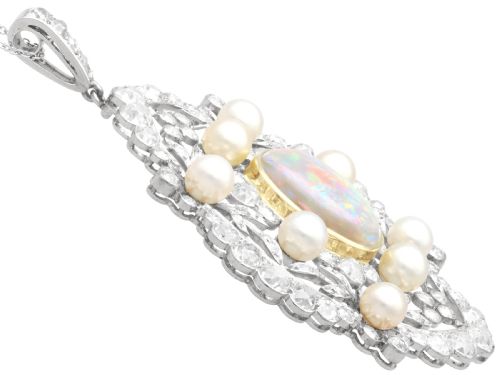 fig 4. An antique platinum pendant featuring a central oval cabochon opal set in gold, surrounded by natural saltwater pearls and openwork diamond filigree.
