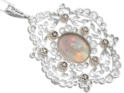 fig 5. An antique platinum pendant featuring a central oval cabochon opal set in gold, surrounded by natural saltwater pearls and openwork diamond filigree.