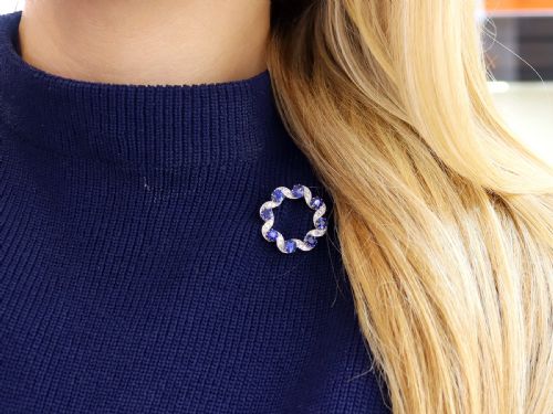 fig 2. A circular late Victorian wreath brooch set with eight oval blue sapphires and diamond-set silver ribbon scroll motifs on a yellow gold frame.