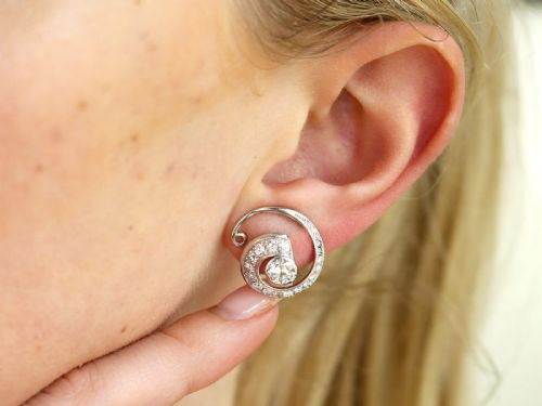 fig 2. A pair of 14ct white gold twirl earrings featuring round brilliant cut diamonds set in a concentric spiral design around a central diamond.