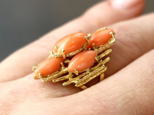 fig 2. A 1960s 14ct yellow gold cocktail ring featuring five marquise cabochon corals set within a textured abstract gold framework.