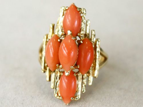 fig 3. A 1960s 14ct yellow gold cocktail ring featuring five marquise cabochon corals set within a textured abstract gold framework.