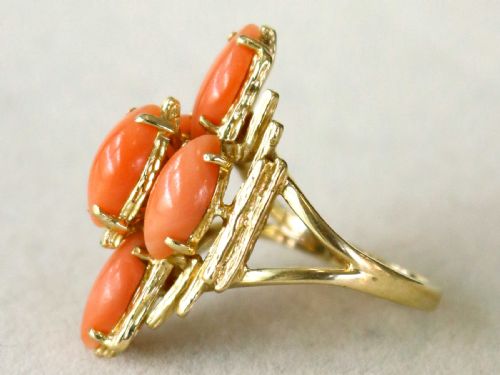 fig 4. A 1960s 14ct yellow gold cocktail ring featuring five marquise cabochon corals set within a textured abstract gold framework.