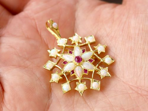 fig 2. An antique 15ct yellow gold starburst pendant brooch set with cabochon opals and faceted rubies suspended on a gold chain.