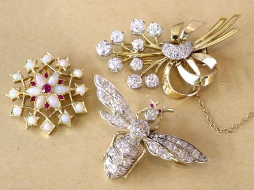 fig 3. An antique 15ct yellow gold starburst pendant brooch set with cabochon opals and faceted rubies suspended on a gold chain.