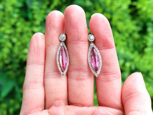 fig 1. Pair of Art Deco platinum drop earrings featuring navette-cut pink tourmalines bordered by small diamonds, suspended from round diamond studs.