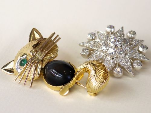 fig 2. An antique Edwardian silver-topped diamond star brooch featuring a central round diamond surrounded by diamond-paved star rays and ball terminals.
