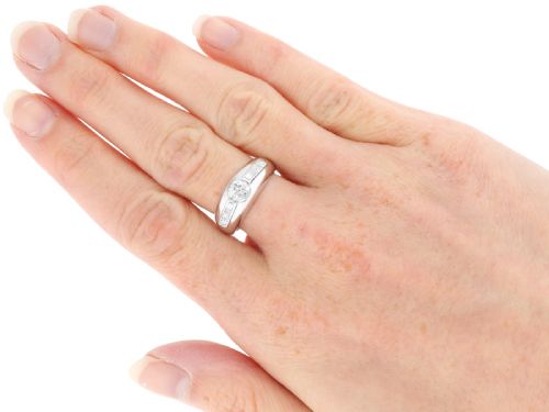 fig 4. A vintage platinum ring featuring a centre round brilliant diamond flanked by baguette and round cut diamonds set into a broad band.