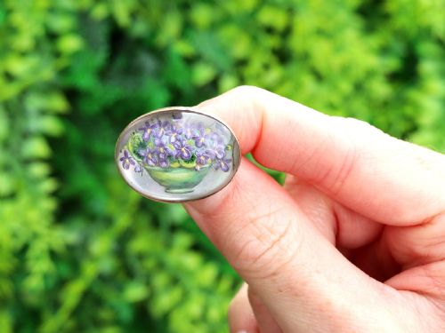 fig 1. An oval 14ct yellow gold brooch set with a reverse-carved glass cabochon displaying purple violets in a green vase.
