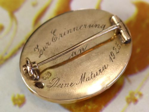 fig 3. An oval 14ct yellow gold brooch set with a reverse-carved glass cabochon displaying purple violets in a green vase.