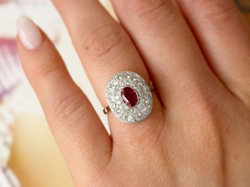 fig 2. An 18ct white gold halo ring featuring a central oval red ruby surrounded by two tiers of round diamonds.