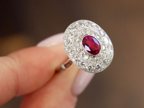 fig 3. An 18ct white gold halo ring featuring a central oval red ruby surrounded by two tiers of round diamonds.
