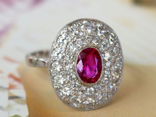 fig 4. An 18ct white gold halo ring featuring a central oval red ruby surrounded by two tiers of round diamonds.