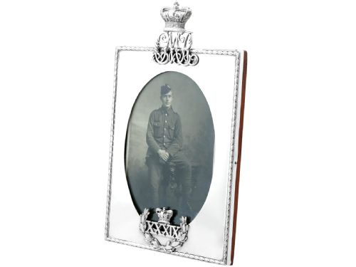 fig 1. A rectangular sterling silver picture frame featuring an oval aperture, topped with a royal crown monogram and detailed with a laurel wreath emblem at the base.