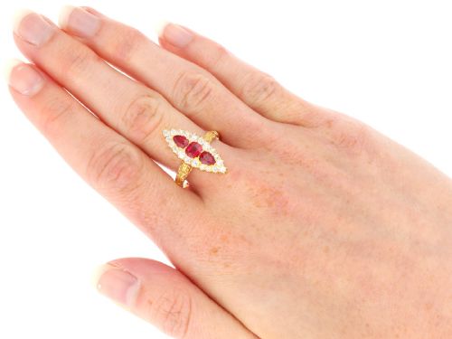 fig 8. An antique 18ct yellow gold navette dress ring featuring three central red rubies surrounded by a border of diamonds and finished with scroll-carved shoulders.