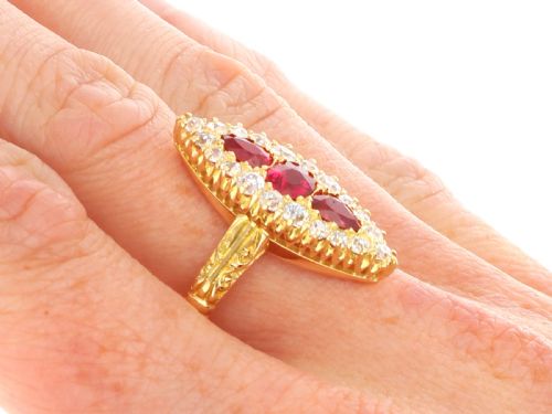 fig 9. An antique 18ct yellow gold navette dress ring featuring three central red rubies surrounded by a border of diamonds and finished with scroll-carved shoulders.