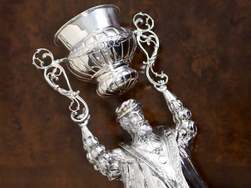 fig 3. A Victorian sterling silver wager cup depicting a bearded male figure holding a double-handled vessel above his head.