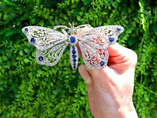 fig 1. An antique butterfly brooch constructed from gold and silver, featuring openwork wings set with diamonds, sapphire details, and green emerald eyes.