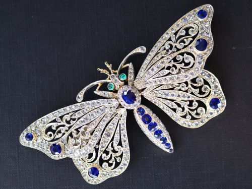 fig 3. An antique butterfly brooch constructed from gold and silver, featuring openwork wings set with diamonds, sapphire details, and green emerald eyes.