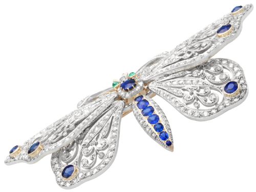 fig 5. An antique butterfly brooch constructed from gold and silver, featuring openwork wings set with diamonds, sapphire details, and green emerald eyes.