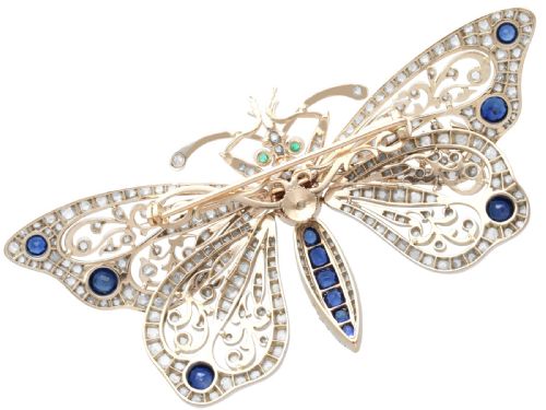 fig 6. An antique butterfly brooch constructed from gold and silver, featuring openwork wings set with diamonds, sapphire details, and green emerald eyes.
