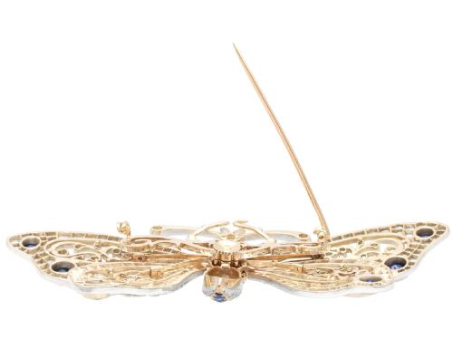 fig 7. An antique butterfly brooch constructed from gold and silver, featuring openwork wings set with diamonds, sapphire details, and green emerald eyes.