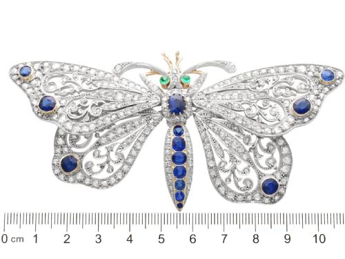 fig 8. An antique butterfly brooch constructed from gold and silver, featuring openwork wings set with diamonds, sapphire details, and green emerald eyes.