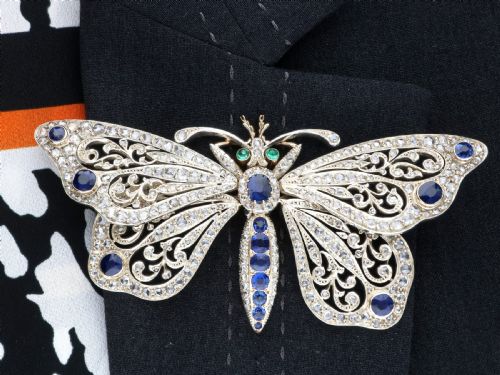 fig 9. An antique butterfly brooch constructed from gold and silver, featuring openwork wings set with diamonds, sapphire details, and green emerald eyes.