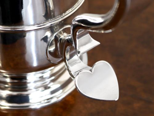 fig 4. A George II sterling silver lidded tankard featuring a domed top, scroll handle, moulded girdle, and engraved foliage decoration.