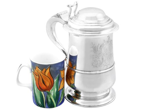 fig 5. A George II sterling silver lidded tankard featuring a domed top, scroll handle, moulded girdle, and engraved foliage decoration.