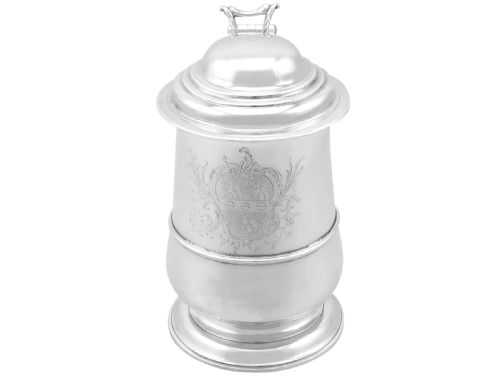 fig 6. A George II sterling silver lidded tankard featuring a domed top, scroll handle, moulded girdle, and engraved foliage decoration.