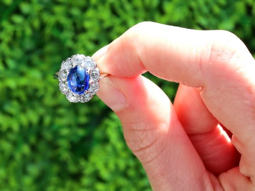 fig 1. An antique 14ct white gold ring featuring an oval cabochon blue sapphire surrounded by a halo of round diamonds.