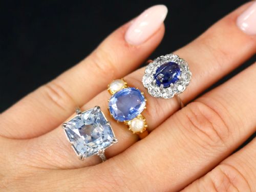 fig 2. An antique 14ct white gold ring featuring an oval cabochon blue sapphire surrounded by a halo of round diamonds.