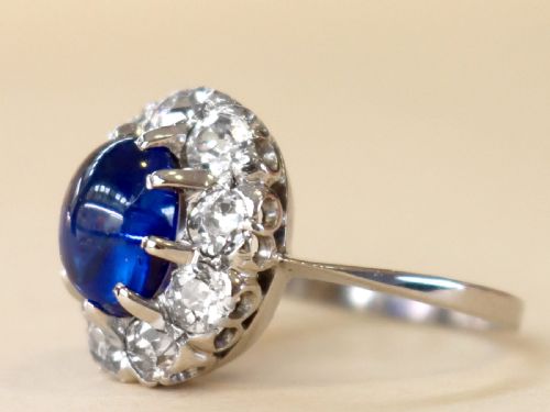fig 4. An antique 14ct white gold ring featuring an oval cabochon blue sapphire surrounded by a halo of round diamonds.